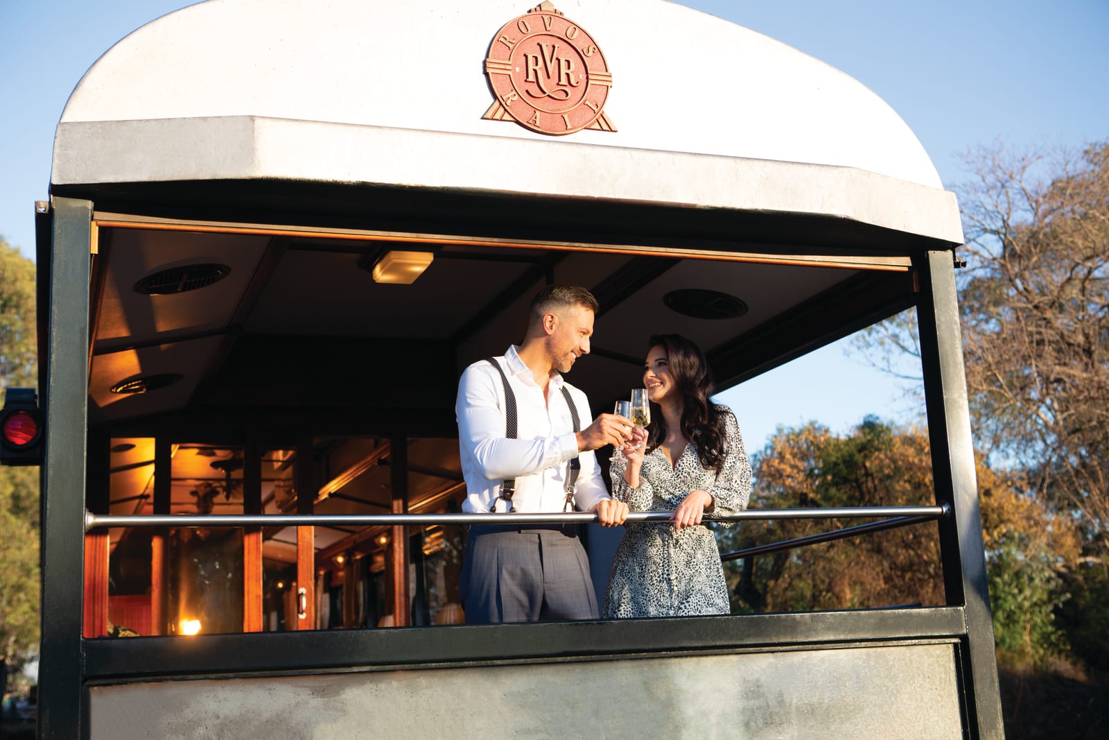 Guests standing on the open-air observation balcony of a Rovos Rail train