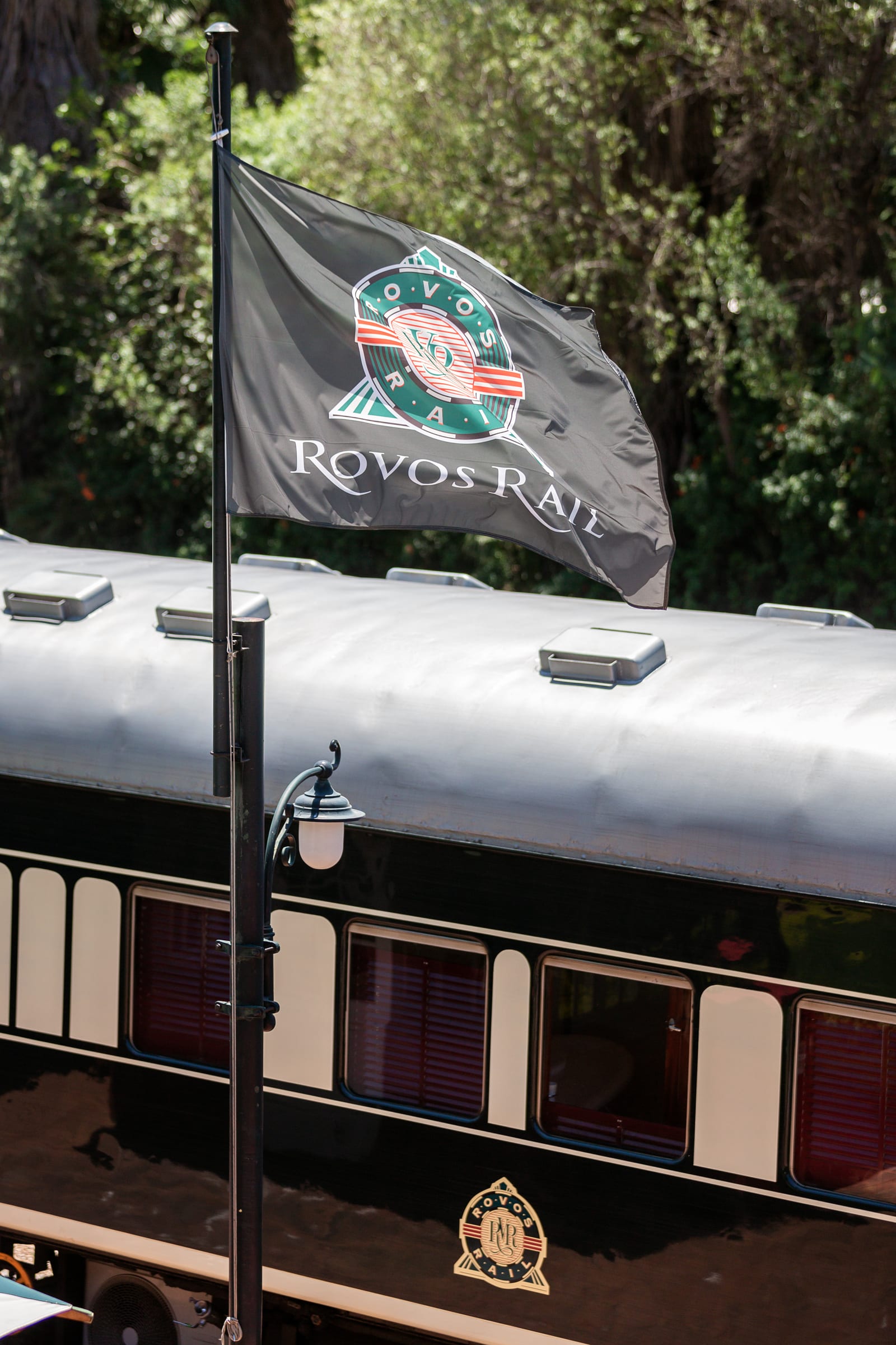 Rovos Rail flag flying above a cream-and-green passenger coach