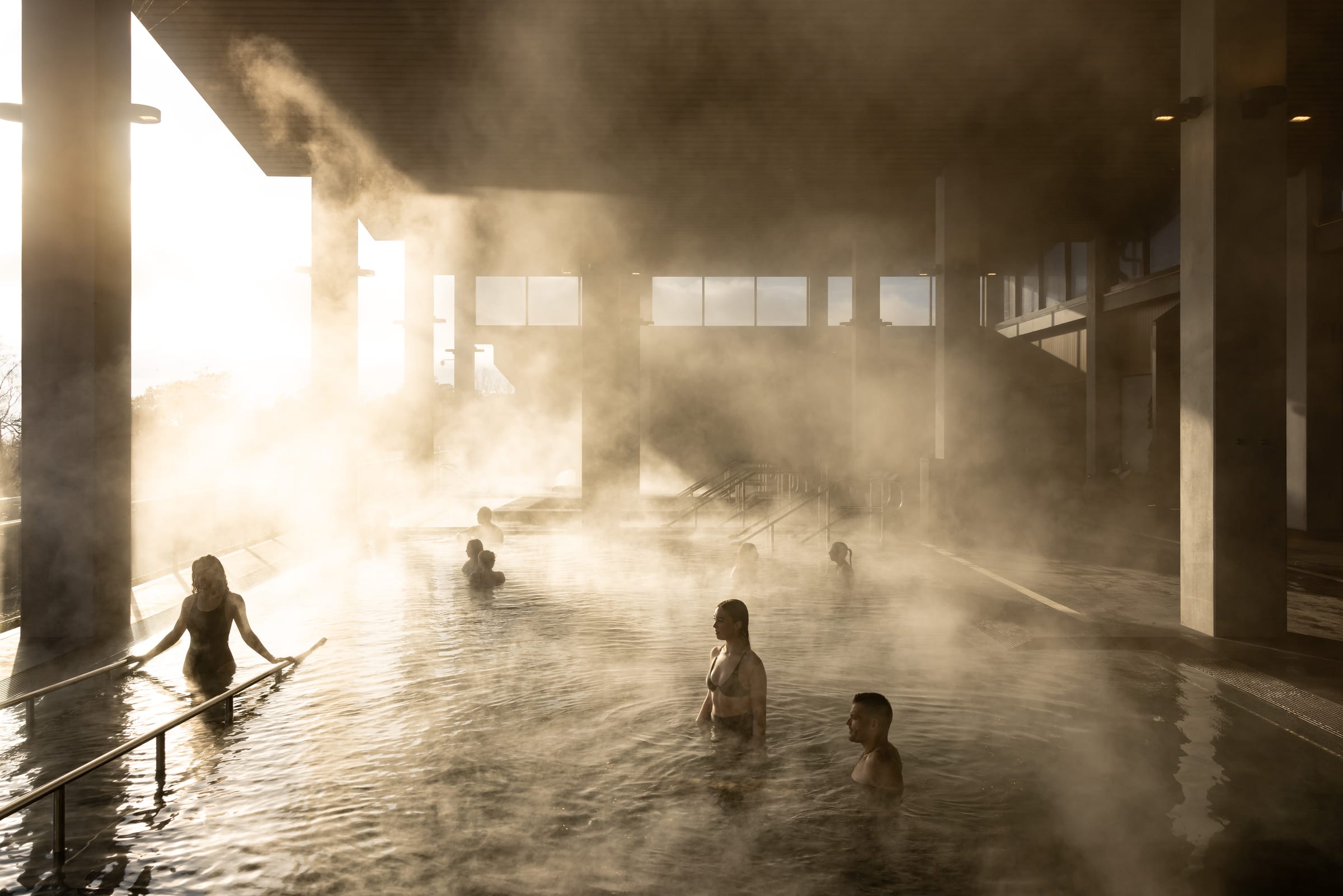 Travelers bathing in geothermal pools with steam rising at Rotorua